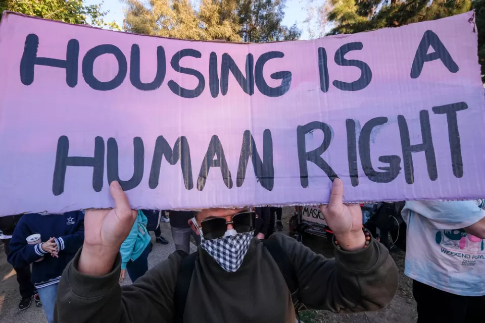 Protester at Echo Park Lake, Los Angeles holding sign that says "Housing is a human right"